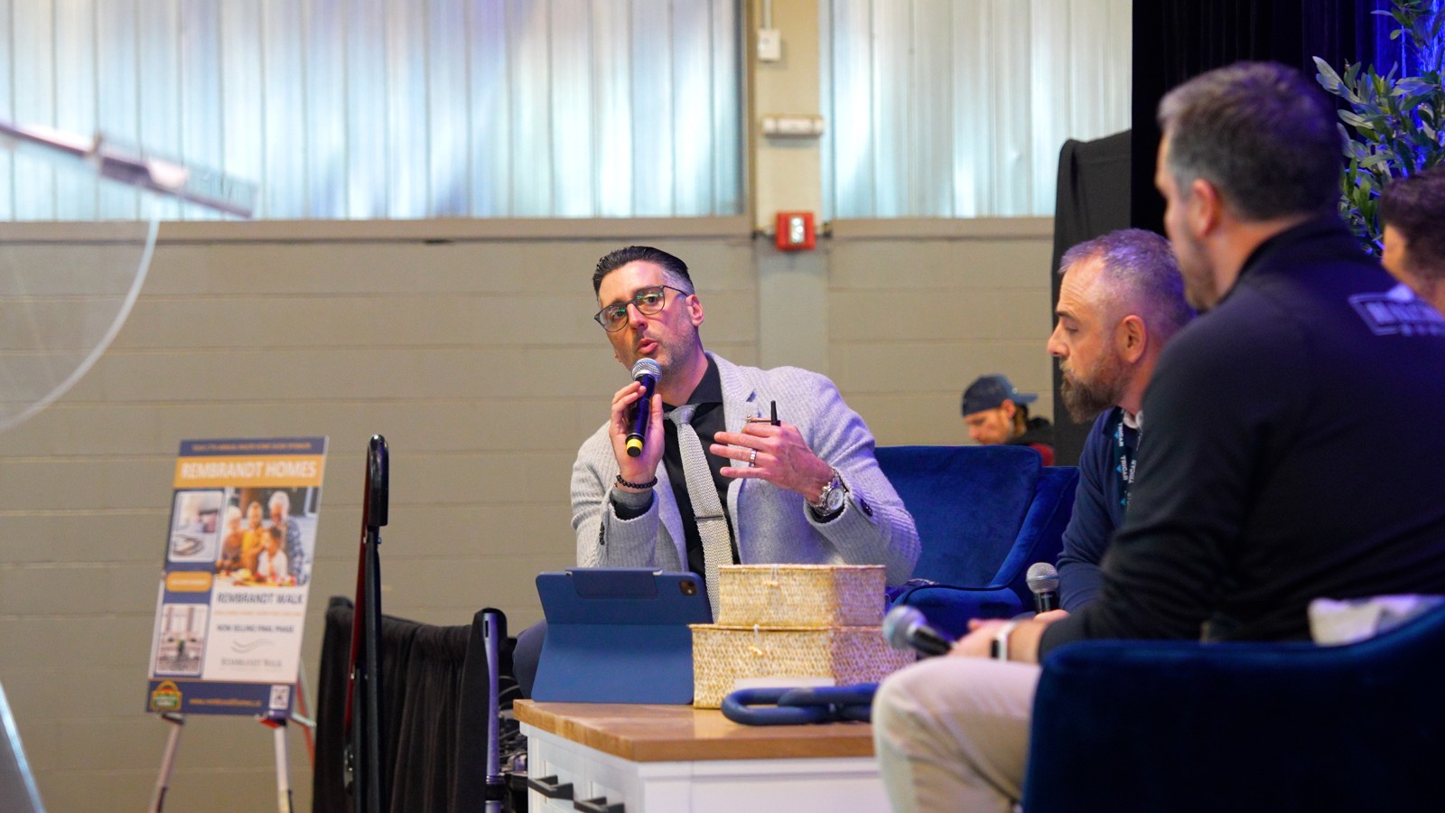 Justin Konikow holding a microphone during an LHBA Lifestyle Home Show panel